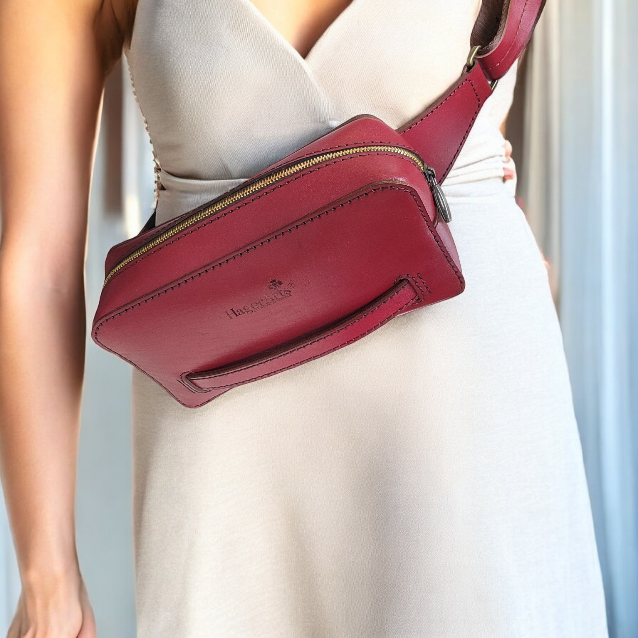 A person wearing a red leather belt bag with a shoulder strap, displayed in a vertical orientation.